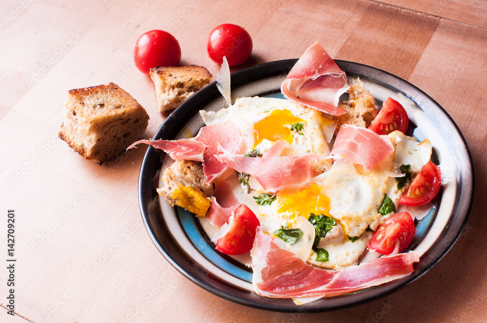 Breakfast of eggs and jamon and tomatoes.