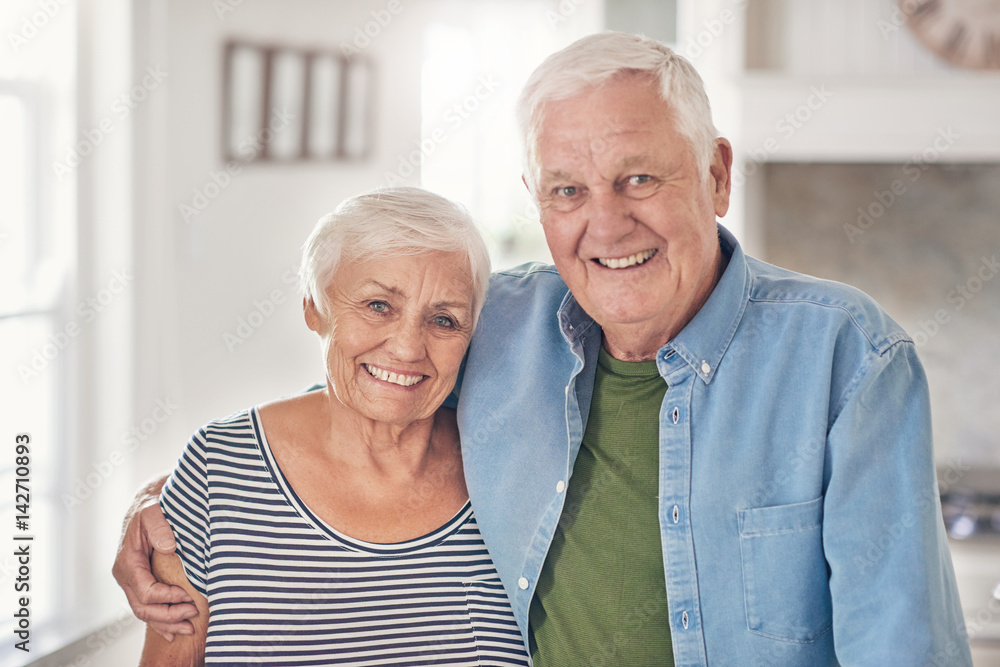 Content senior couple standing together at home in their kitchen Content senior couple standing together at home in their kitchen