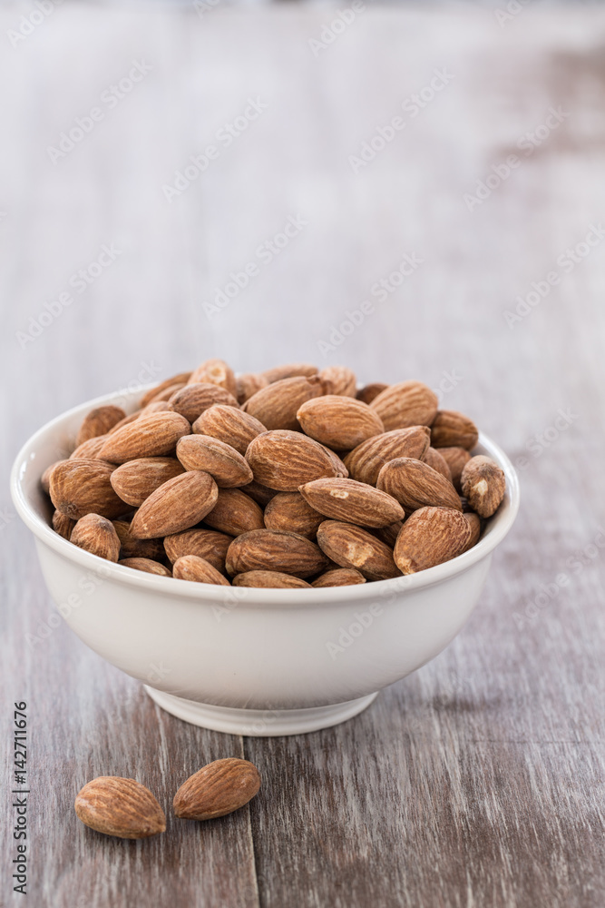 White Bowl of Almonds on Wood Background White Bowl of Almonds on Wood Background