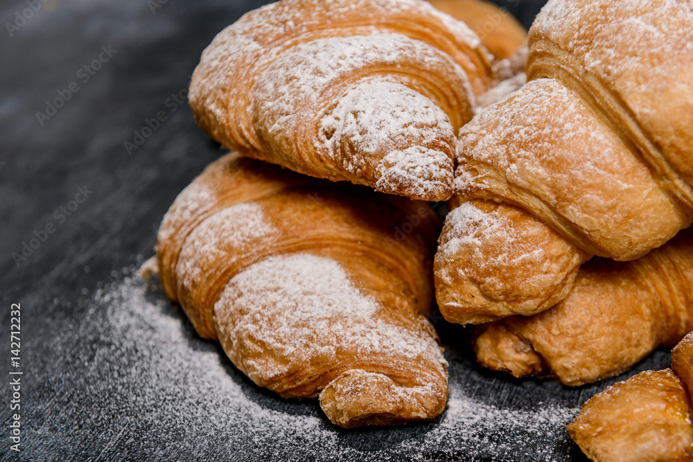 Macro picture of croissants with powdered sugar on grey table. 