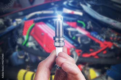 Tableau sur toile Mechanic holds a spare part spark plug in his hand