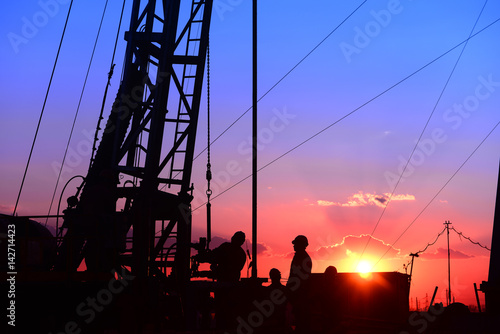 The oil workers in work, under the background of the setting sun