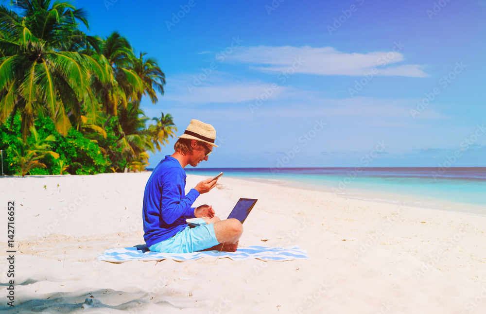 man with laptop and mobile phone on tropical beach