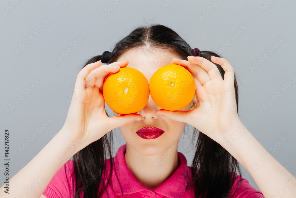 Beautiful close-up young woman with oranges. Healthy food concept. Skin care and beauty. Vitamins and minerals. gray background Beautiful close-up young woman with oranges. Healthy food concept. Skin care and beauty. Vitamins and minerals. gray background