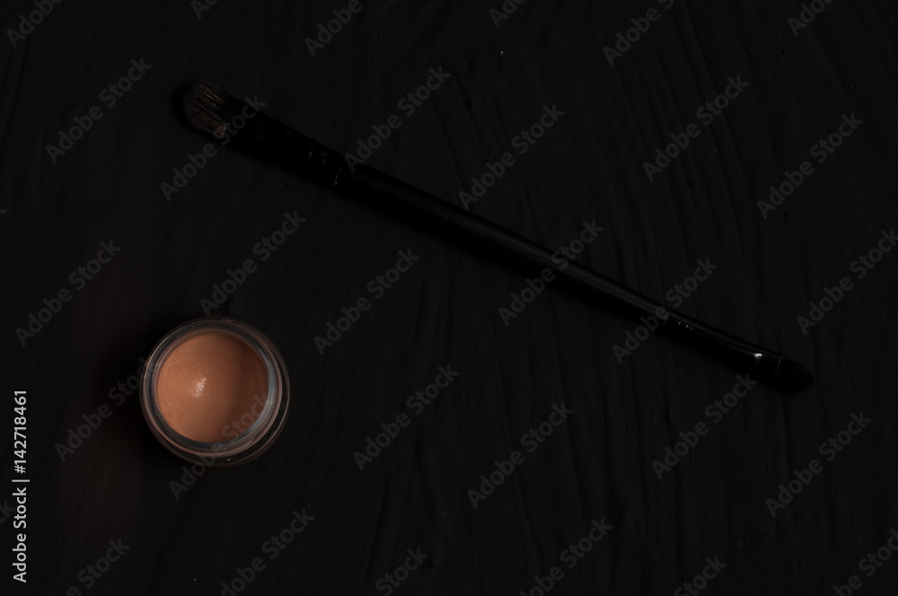 Bright brown eye shadows and sponge brushes for foundation black background Bright brown eye shadows and sponge brushes for foundation black background