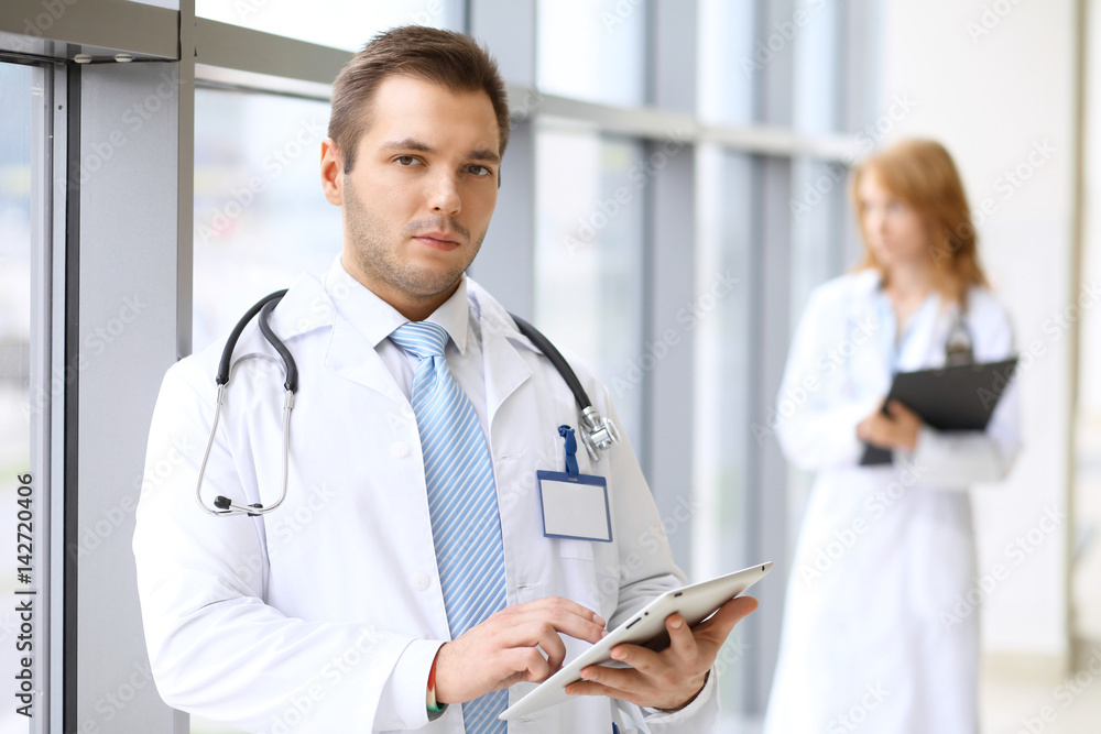 Smiling doctor waiting for his team while standing upright Smiling doctor waiting for his team while standing upright
