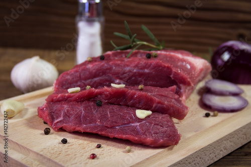 Raw beef steak on wooden table with rosemary