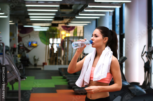 Girl is refreshing at the gym with a bottle of water