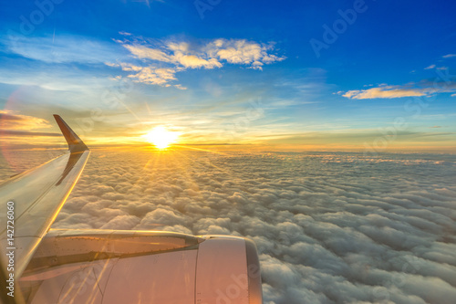 Plane wing on the sky with sunset and cloud, aerial view from airplane window.