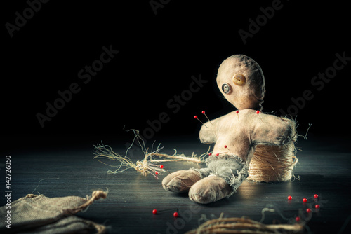 Voodoo doll with dramatic lighting on a wooden background photo