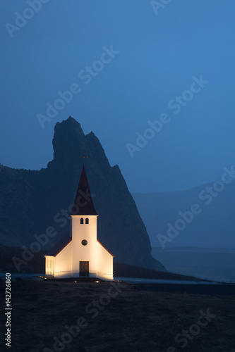 Fotografie Vik i Myrdal Church in Iceland with mountain in the background taken at dusk