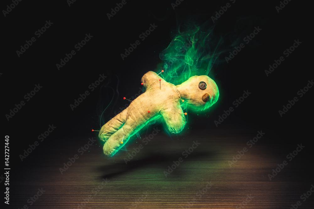 Voodoo doll with dramatic lighting on a wooden background - obrazy, fototapety, plakaty 