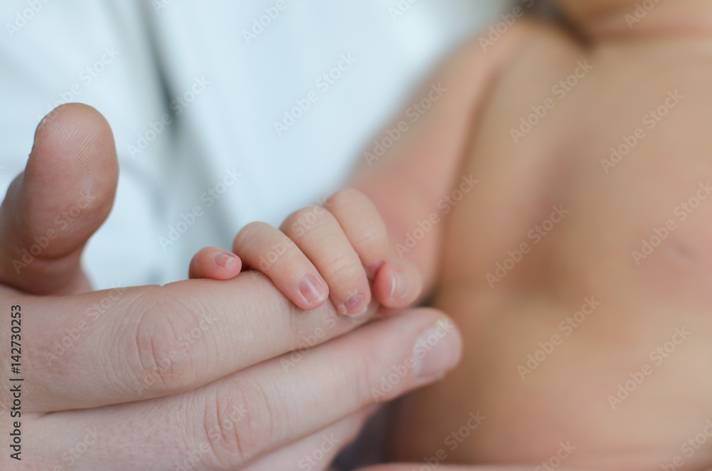 Father holds the hand of a newborn baby boy Father holds the hand of a newborn baby boy