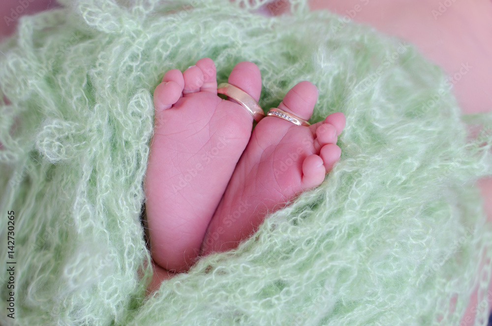 Wedding rings of parents on the feet of a newborn baby boy Wedding rings of parents on the feet of a newborn baby boy