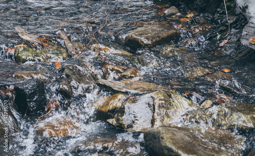 Проточная вода горного ручья. Ледяная холодная вода и каменные глыбы