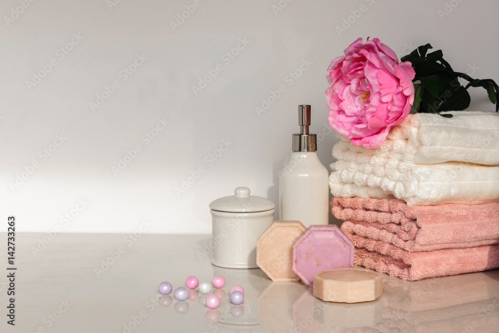 Bath setting in white and pink colors. Towel, aroma oil, flowers, soap. Selective focus, horizontal. Bath setting in white and pink colors. Towel, aroma oil, flowers, soap. Selective focus, horizontal.