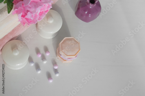 Bath setting in white and pink colors. Towel, aroma oil, flowers, soap. Selective focus, horizontal.