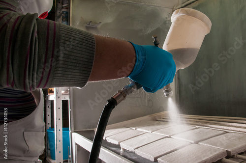 Pottery artisan in Caltagirone, Sicily, using an airbrush to enamel some square tiles photo