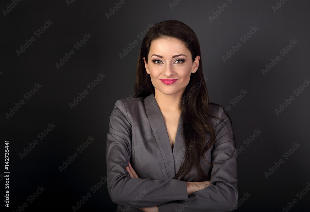 Beautiful smiling business woman in grey suit looking happy with folded arms on dark background with empty space Beautiful smiling business woman in grey suit looking happy with folded arms on dark background with empty space