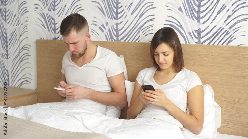 couple with smartphones in bed couple with smartphones in bed