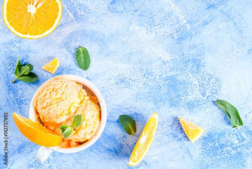 Homemade organic orange sorbet with orange slices and mint leaves. On a blue stone table   copy space top view photo