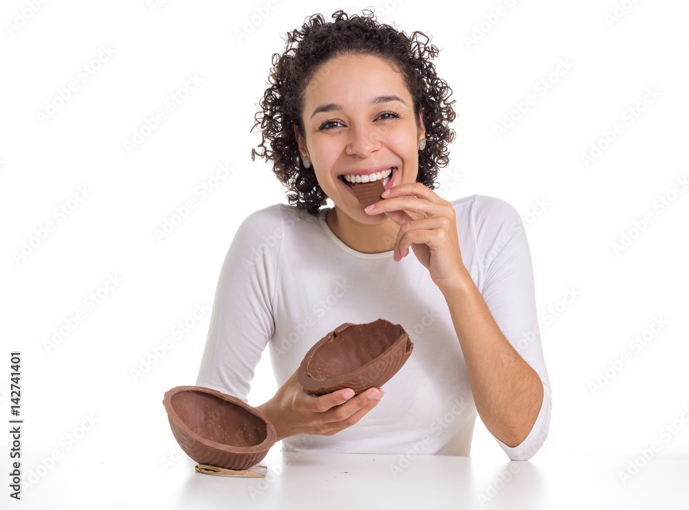 Obraz premium Young girl smiles and looks like chocolate bonbon. Easter egg next to you.