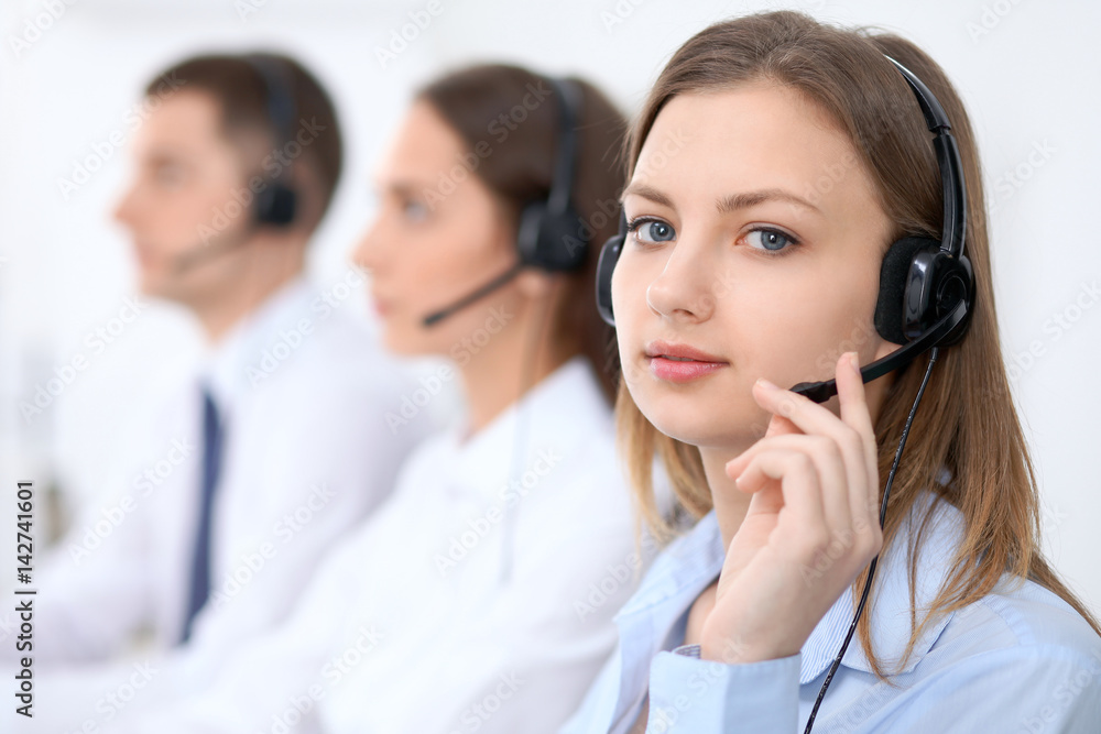 Call center operators. Focus at young beautiful business woman in headset. Call center operators. Focus at young beautiful business woman in headset.