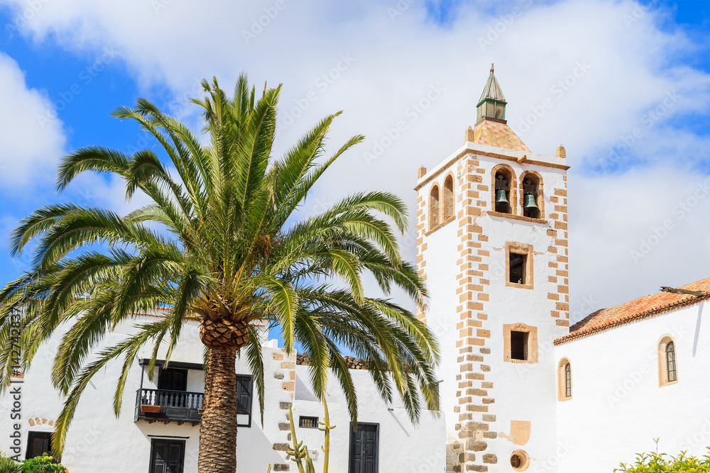 Palm tree and tower of Cathedral Santa Maria de Betancuria, famous landmark of Fuerteventura, Canary Islands, Spain Palm tree and tower of Cathedral Santa Maria de Betancuria, famous landmark of Fuerteventura, Canary Islands, Spain