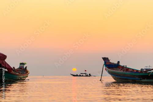 Long Tail boats at sunset with boat passing under sun, Koh Tao, Thailand