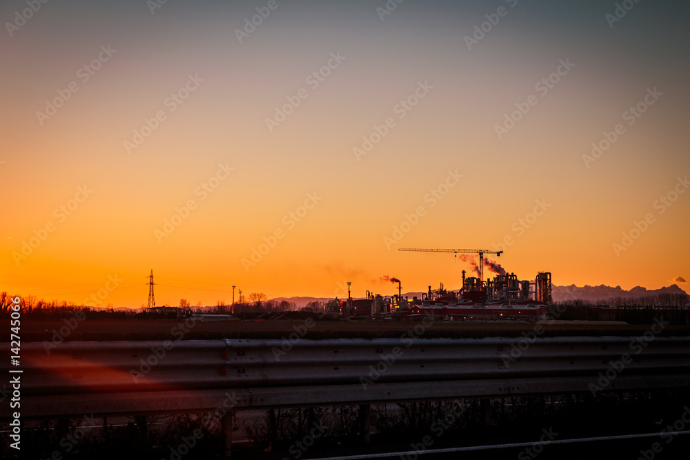 sun goes down behind an industry