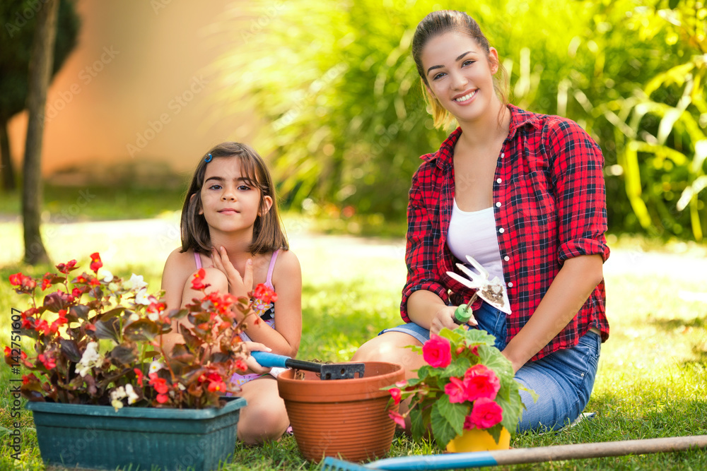 Young mother and her cute little daughter are gardening together in front or back yard