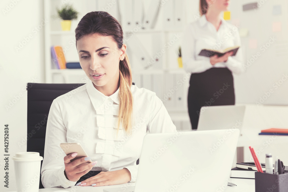 Serious woman looking at phone in office, toned Serious woman looking at phone in office, toned