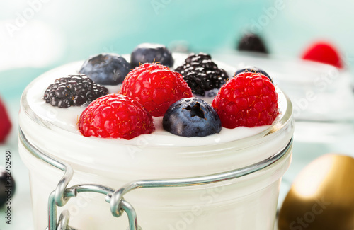 Jar of yogurt with blueberries, blackberries and raspberries.