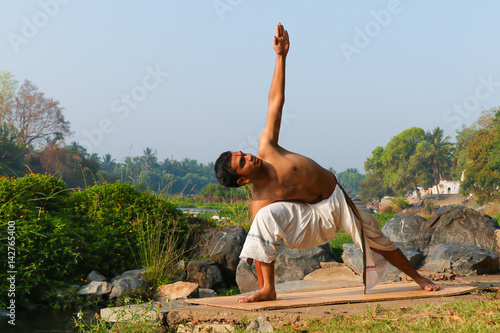 Canvas Print An Indian yogi performing yoga asanas on a riverbank in India.