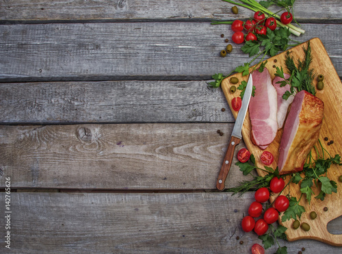 wooden background with ham, tomatoes, green dill and parsley on cutting board for food blog