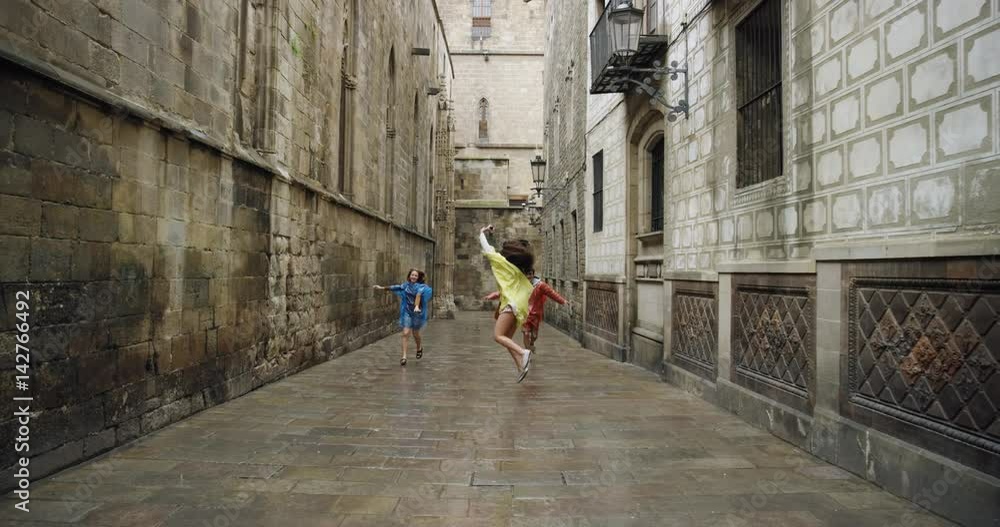 Diverse group of friends dancing freestyle in European City wearing multi colored poncho rain coats in rainy weather celebrating travel adventure Diverse group of friends dancing freestyle in European City wearing multi colored poncho rain coats in rainy weather celebrating travel adventure