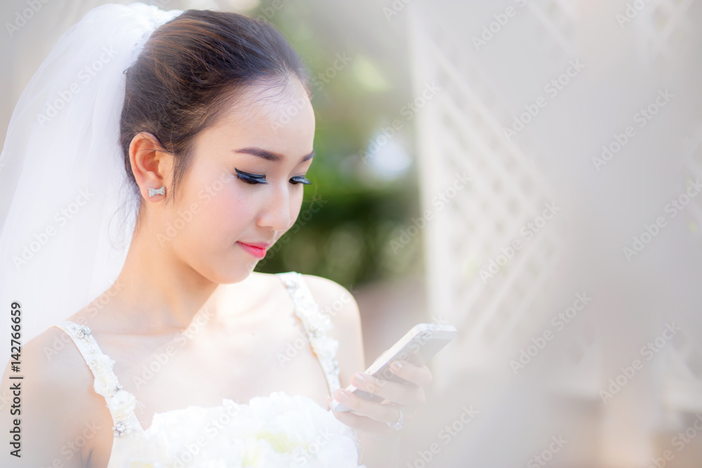 Happy bride talking on cell phone in wedding dress