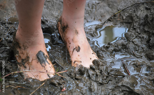 Kid's muddy feet. Selective focus.