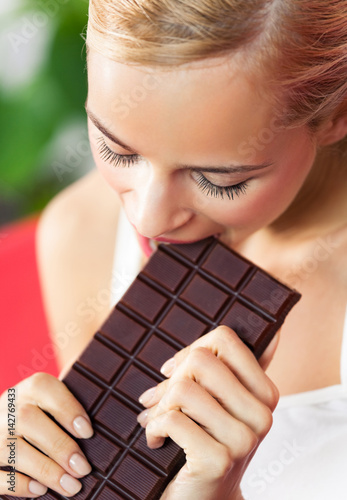 Young beautiful woman eating chocolate at home