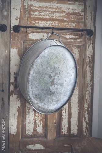 Old stylish iron tub hanging on a wooden wall