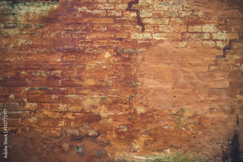 Grunge brick wall with peeling orange paint