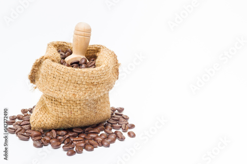 Organic coffee beans and wooden coffee dipper on white background close up isolated.