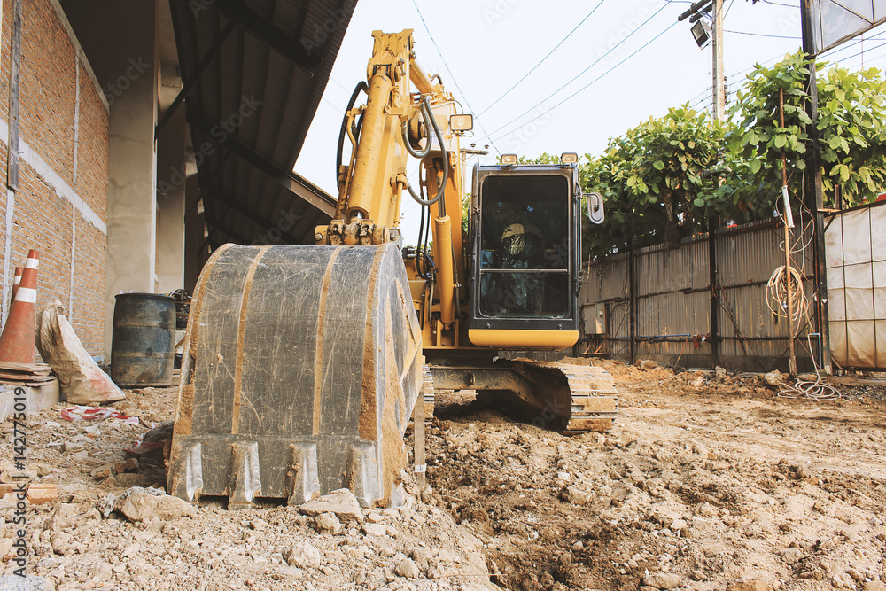 Fototapeta premium Excavator loader or backhoe at a construction site with soft-focus in the background. over light