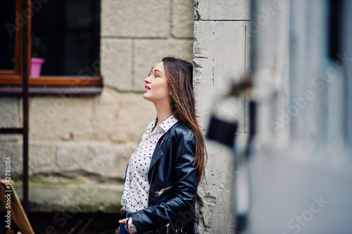 Portrait of stylish young girl wear on leather jacket and ripped jeans at streets of city. Street fashion model style.