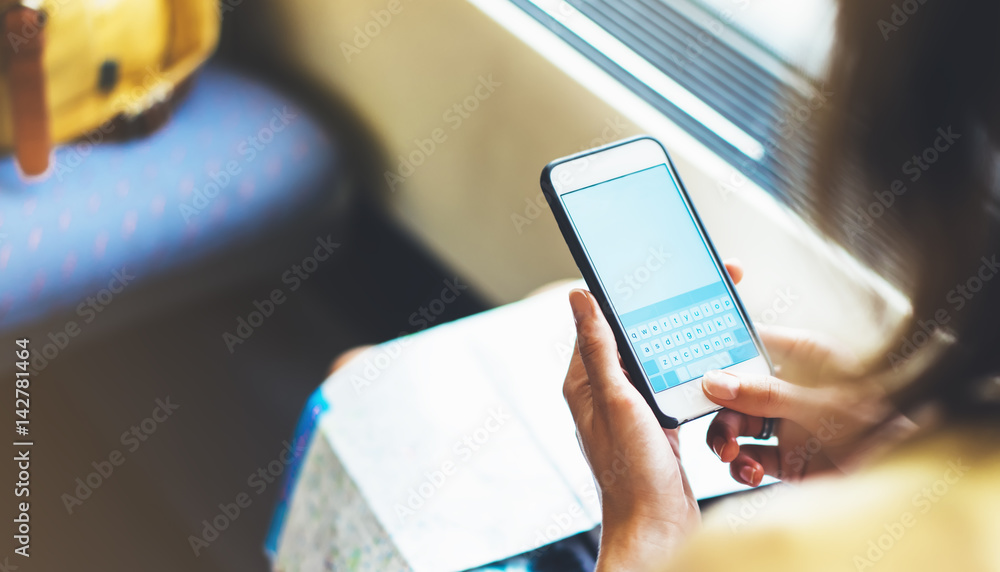 Enjoy travel. Young pretty woman travel by train sitting near the window using smartphone and looking map. Tourist texting online message and plan route of railway, railroad transport concept mock up