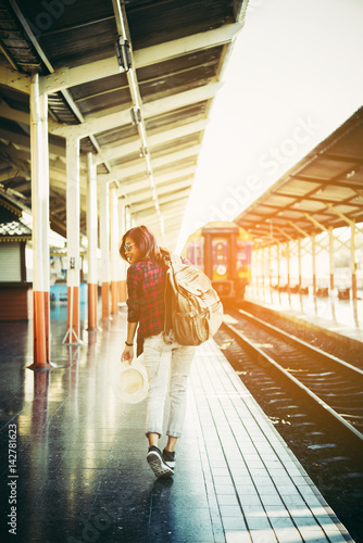 Young hipster woman waiting on the station platform with backpack. Travel concept.
