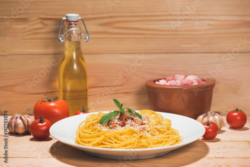 Plate of tasty spaghetti with tomato sauce and meat on wooden table.