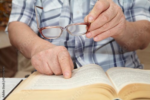 An elderly man with glasses reading a book