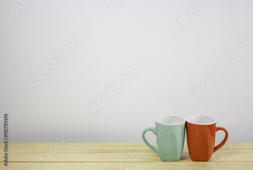 green and red coffee mug on wooden table. focus on mug