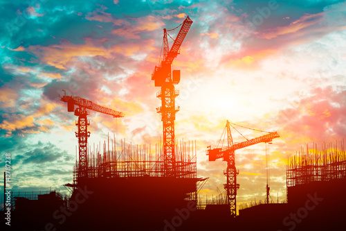 Canvas-taulu Crane and building construction site at sunset